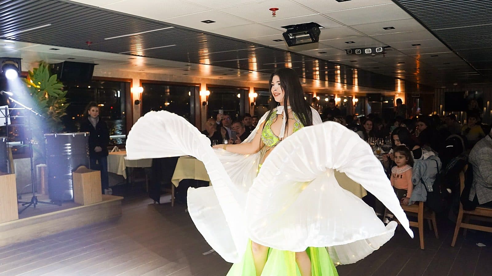 Oriental dancer with illuminated wings performing for dinner guests