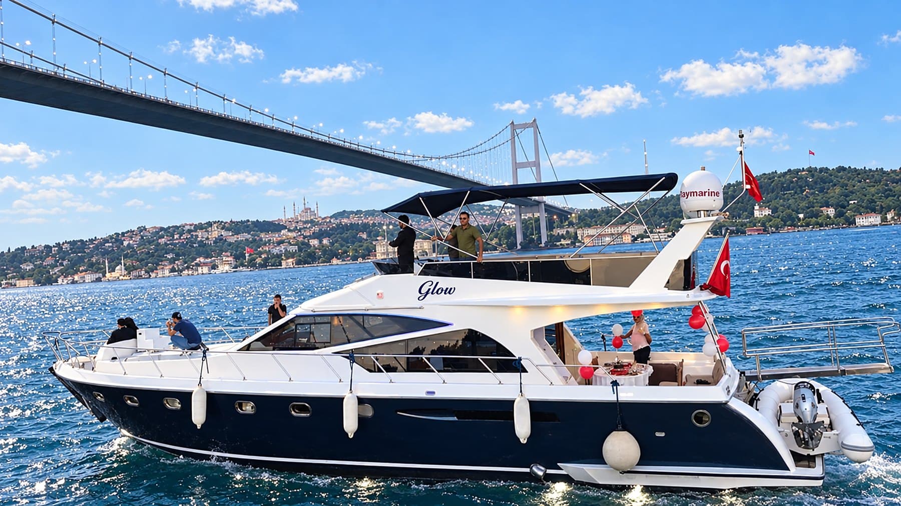 Private yacht decorated for a celebration, sailing under the Bosphorus bridge in daylight